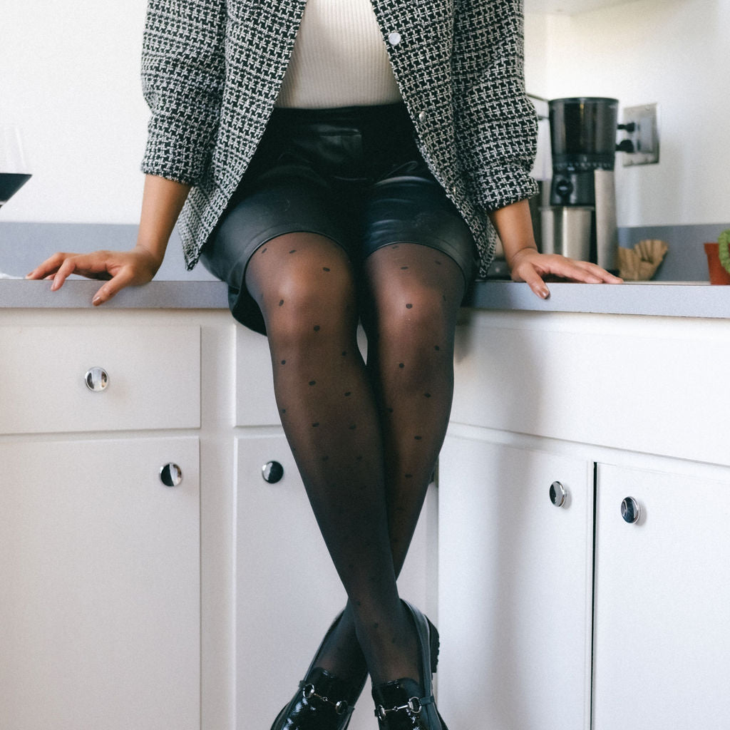 Woman sitting on a kitchen counter in sheer black pin dot tights